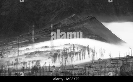 Misty fluente attraverso il villaggio di mattina presto come il sorgere del sole, bromo, Indonesia Foto Stock