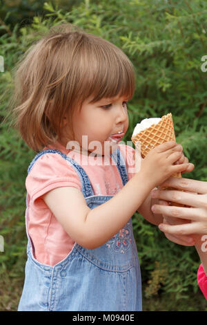 Carino bambina sono mangiare gelato in estate con mettere la lingua di fuori Foto Stock