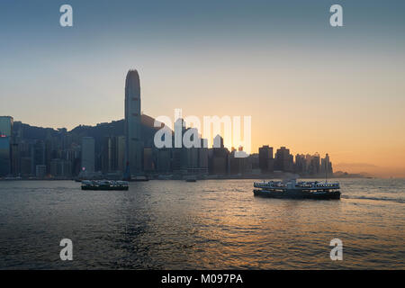 Star traghetti che attraversano il porto di Victoria e di Hong Kong al tramonto. Foto Stock