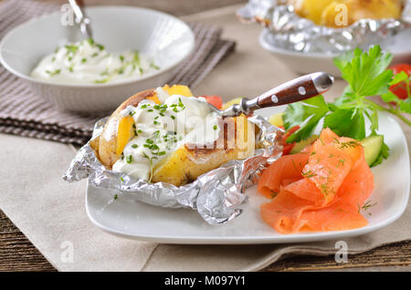 Giacca di patate con panna acida, erbe e salmone affumicato Foto Stock