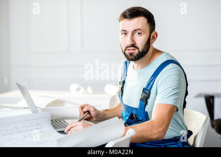 Repairman con disegni su carta in ufficio Foto Stock