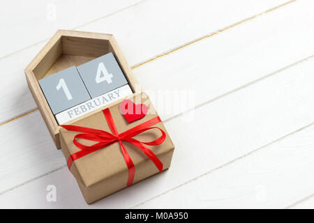 14 febbraio. legno calendario con cuore rosso e scatola regalo sulla parte superiore il giorno di San Valentino card. Copia dello spazio. Foto Stock