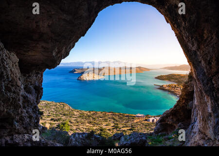 Vista panoramica del golfo di Elounda con isola di Spinalonga. Vista dalla montagna attraverso una grotta, Creta, Grecia. Foto Stock