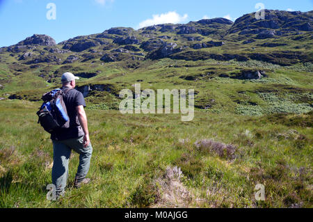 Hillwalker camminando verso la montagna scozzese Corbett Beinn un Choin in Loch Lomond e il Trossachs National Park, Highlands scozzesi, UK. Foto Stock