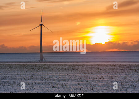 Sunzet oltre olandese innevato paesaggio invernale con turbine eoliche Foto Stock