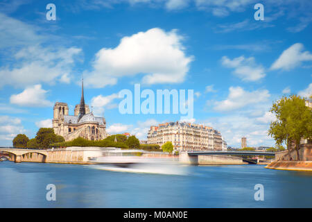 Parigi, panorama della cattedrale di Notre Dame oltre il Fiume Senna su un luminoso giorno di primavera. Una lunga esposizione a sottolineare il movimento di una nave passeggeri su ri Foto Stock