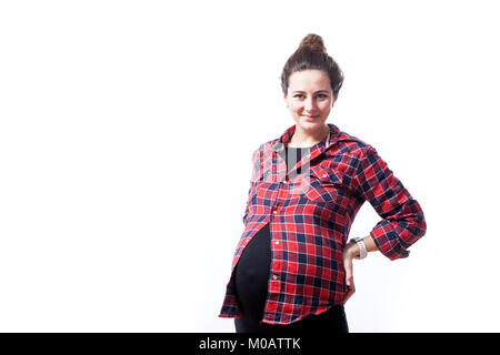 Giovani dai capelli scuri donna a 37 settimane di gravidanza in un abito nero e plaid shirt sorrisi e detiene sul retro isolato su un fondo bianco Foto Stock