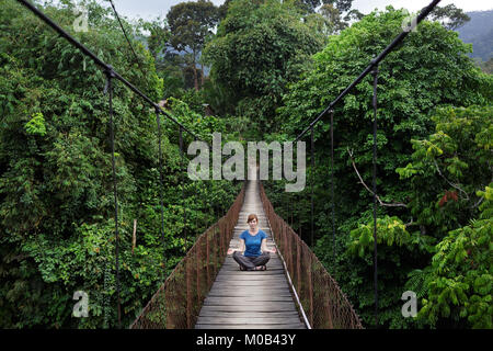 Donna seduta sul ponte sospeso in Gunung Leuser National Park di Tangkahan, Sumatra, Indonesia Foto Stock