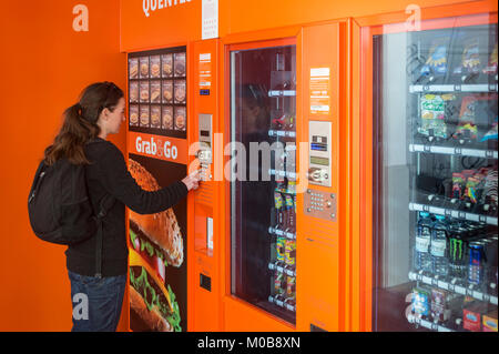 Donna che utilizza un distributore automatico in 24 ora Grab & Go cafe concetto. Foto Stock