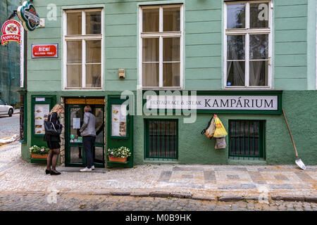 Una coppia entra Kamparium, un ristorante di bistecca a Praga, situato lungo una strada acciottolata in Malá Strana, Praga, Repubblica Ceca Foto Stock