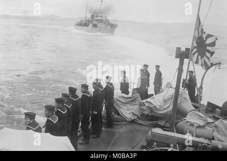 Equipaggio navale sulla nave giapponese saluta un altro e mosche di Admiralty Bandiera Foto Stock