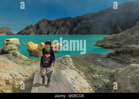 Minatore locale che trasportano i blocchi di zolfo, Ijen, Indonesia Foto Stock