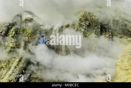 Ranger è circondato da gas tossici cercando di mettere dell'eccesso di fumo dal tubo di scarico aumenta la produzione di zolfo in Kawah Ijen mountain, Indonesia Foto Stock