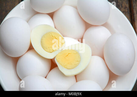 Numerosi white uova sode in bianco ciotola con due metà con forcelle sulla parte superiore Foto Stock