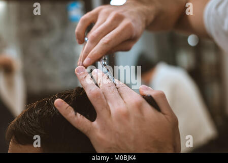 Vista dettagliata del uomo sorridente di ottenere un taglio di capelli da un barbiere Foto Stock