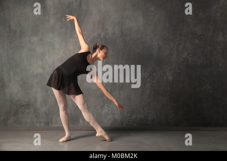 Attraente bella donna bionda baterina in una danza nero tutu, bianco collant e pointe shoes dancing in un buio studio Foto Stock