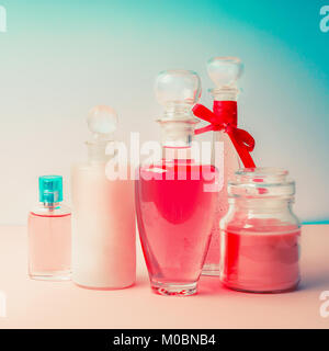 Diverse bottiglie di cosmetici e prodotti di . Confezione per cosmetici raccolta per la crema, saponi, schiume, shampoo e profumo su di un bel colore rosa turchese bl Foto Stock