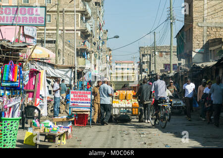 Vista giù per una strada a Huruma, mostrando persone negozi ed edifici, Nairobi, Kenya, Africa orientale Foto Stock