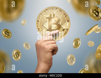 L'uomo mani golden bitcoin con la caduta di bitcoins su sfondo lucido Foto Stock