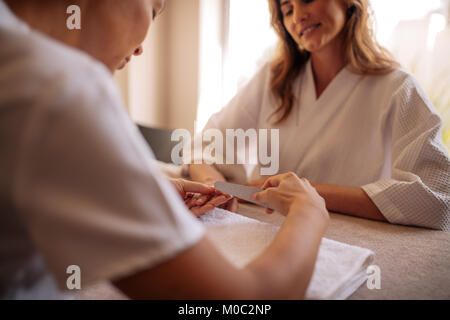 Manicurist femmina facendo manicure per donna in un salone di bellezza. Estetista il deposito di clienti di sesso femminile unghie a spa salone di bellezza Foto Stock