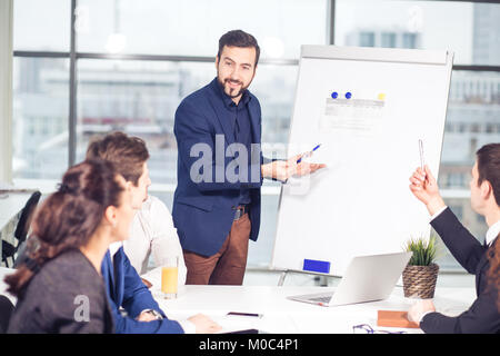 Un gruppo di uomini di affari che guardando il grafico sulla lavagna a fogli mobili Foto Stock