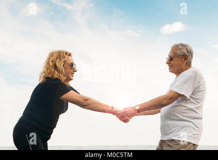 Modello rilasciato: coppia coppia eterosessuale stretching insieme contro il cielo blu all'aperto Foto Stock