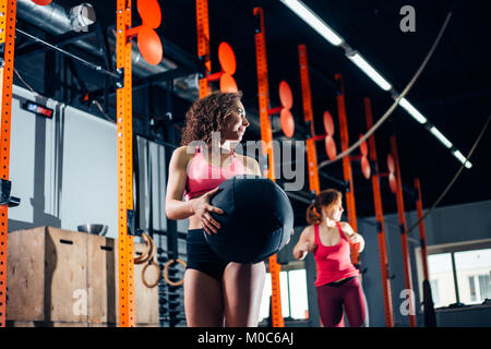 Due donne getta le sfere di medicina in palestra per il fitness Foto Stock