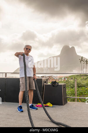 Modello rilasciato: uomo vecchio (80-89) esercitando con combattendo la corda in palestra pubblica a Ipanema, Rio de Janeiro, Brasile Foto Stock