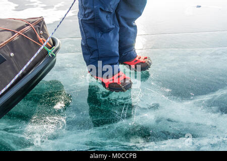 Gambe umane in escursionismo boot in ghiaccio ramponi sulla texture Baikal ghiaccio. Foto Stock