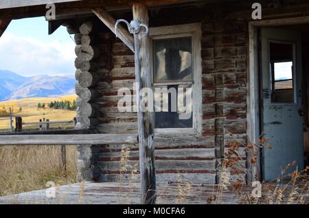 Qui si trova un vecchio abbandonato log cabin, nel mezzo di un campo con una splendida veranda vista sulle montagne e colline Foto Stock