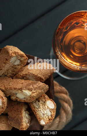 Italian cantuccini biscotti e un bicchiere di vin santo vino su sfondo di legno Foto Stock