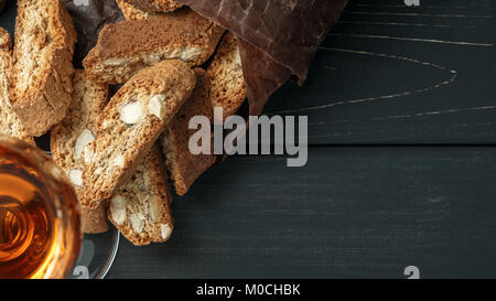 Italian cantuccini biscotti e un bicchiere di vin santo vino su sfondo di legno Foto Stock