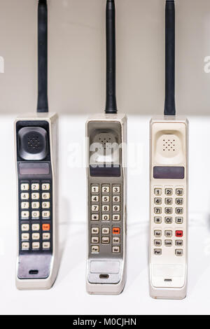 Tre grandi vintage verticale portatile vecchio obsoleti telefoni cellulari in piedi sul display con i pulsanti Foto Stock