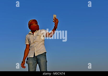 Gli uomini nel deserto di sabbia giocando ed appendere fuori con i telefoni cellulari e rendendo selfies Foto Stock