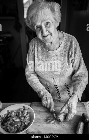 Una donna anziana trita i pomodori per insalata. Foto in bianco e nero. Foto Stock