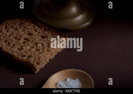 Pezzo ruvido pane di segale con sale grosso su uno sfondo di legno ancora vita Foto Stock