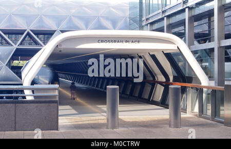 L'ingresso a Crossrail posto a Canary Wharf stazione con un genitore e bambino su uno scooter entrando nel architettonico moderno tunnel tunnel Foto Stock