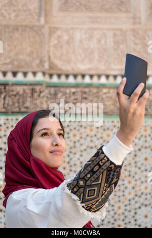 La donna araba in abbigliamento tradizionale tenendo selfie con telefono mobile Foto Stock