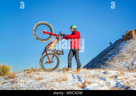 Ciclista maschio in sella a una moto di grasso in inverno Colorado paesaggio pedecollinare - Lory parco dello stato Foto Stock