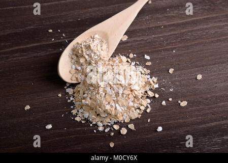 Manciata di avena e cucchiaio su uno sfondo di legno Foto Stock