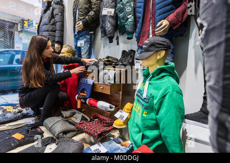 Salonicco, Grecia - 19 Gennaio 2018: Donna decora la finestra alla vetrina di un negozio di abbigliamento nel centro di Salonicco in vista dell'inverno sconti Foto Stock