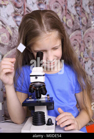 Ragazza con interesse guardando attraverso un microscopio Foto Stock