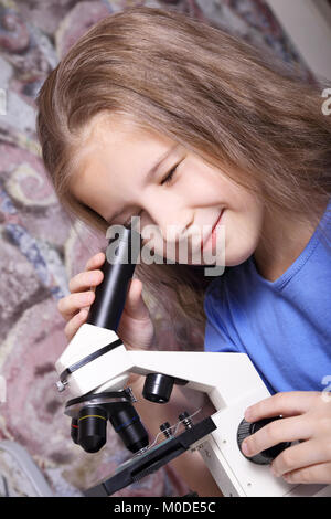 Ragazza con interesse guardando attraverso un microscopio Foto Stock