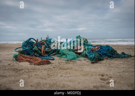 Un groviglio di materiale plastico sintetico le funi di pesca lavato fino sulla spiaggia. Il danno ambientale. Foto Stock