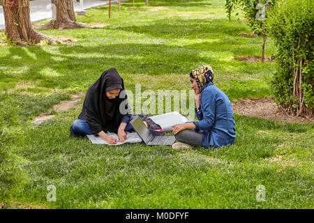 Isfahan, Iran - 24 Aprile 2017: due musulmani studenti femmina, vestito di hijab islamico, si stanno preparando per gli esami, seduto sul prato in città par Foto Stock