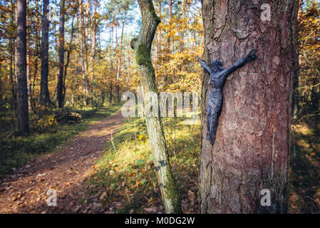 Cristo la figura su un albero accanto alla II Guerra Mondiale tomba del Soldato sconosciuto nella foresta di Kampinos, grandi foreste complesso in Masovian voivodato di Polonia Foto Stock
