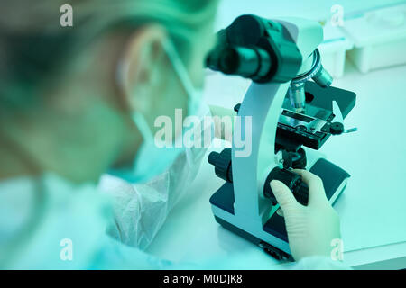 Donna con microscopio in laboratorio Foto Stock