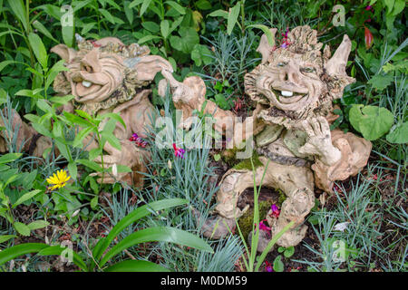 Giardino decorativo gnomi con onr naughty dentata sorrisi seduta di fiori ed erba nel bellissimo giardino Foto Stock