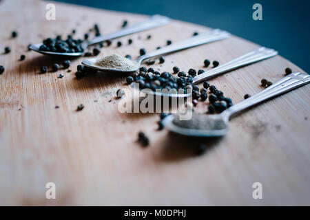 Vari tipi di pepe su uno sfondo di legno Foto Stock