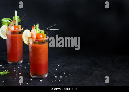 Bloody Mary Cocktail in bicchieri con contorni. Il pomodoro Bloody Mary bevanda piccante su sfondo nero con copia spazio. Foto Stock